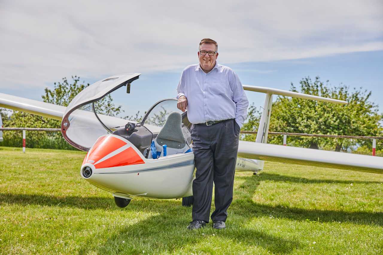 Andreas Ruck neben einem Segelflugzeug auf einer Wiese.